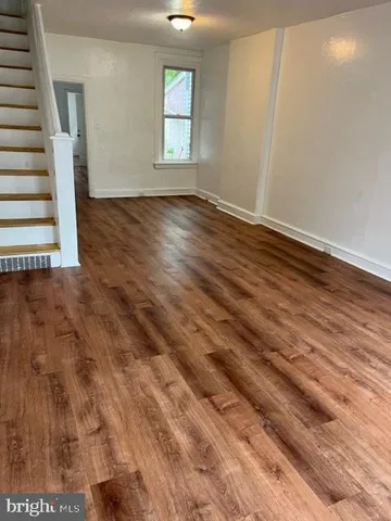 a view of an empty room with wooden floor and window