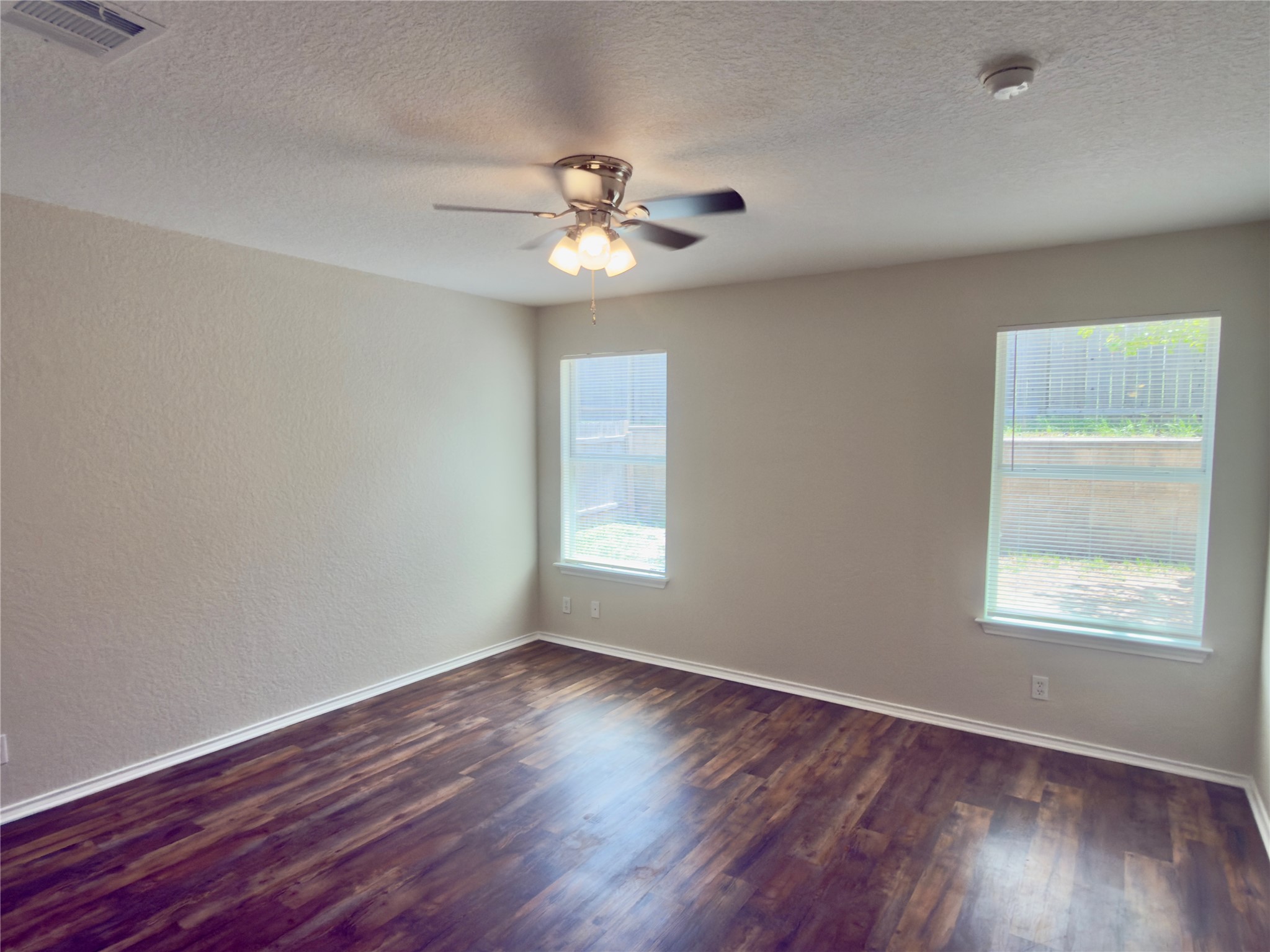 255 Myrtle Street Kyle, TX 78640 - Photo 15 of 31 Spacious room featuring wood-finish flooring, neutral-toned walls, and a ceiling fan with integrated lighting