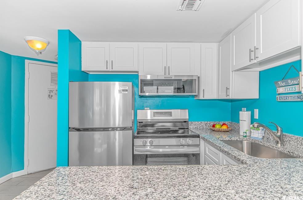 1605 South Ocean Boulevard, Unit 705 Myrtle Beach, SC 29577 - Photo 13 of 38 Kitchen featuring light stone countertops, stainless steel appliances, and white cabinets