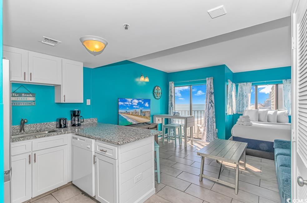 1605 South Ocean Boulevard, Unit 705 Myrtle Beach, SC 29577 - Photo 35 of 38 Kitchen featuring white cabinetry, dishwasher, light stone counters, a peninsula, and light tile patterned floors