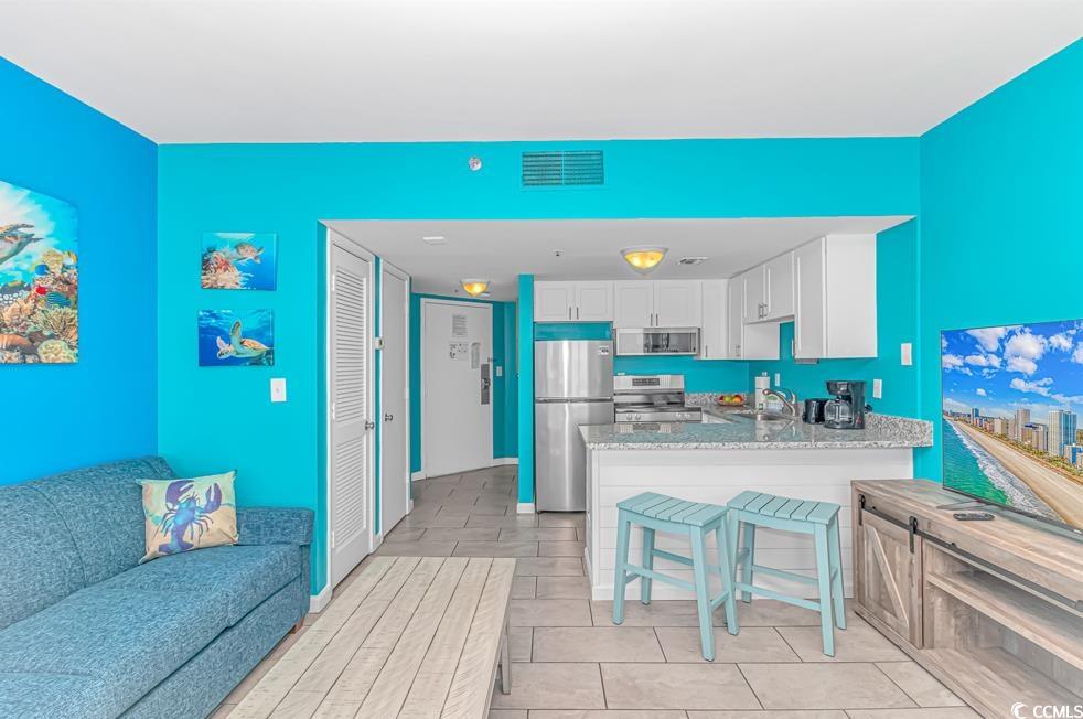 1605 South Ocean Boulevard, Unit 705 Myrtle Beach, SC 29577 - Photo 7 of 38 Kitchen with stainless steel appliances, white cabinetry, light stone counters, and a peninsula