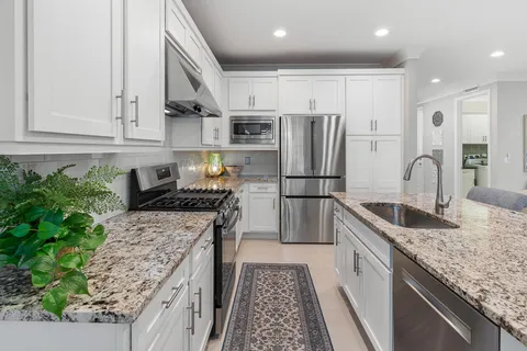 a kitchen with stainless steel appliances granite countertop a refrigerator and a stove