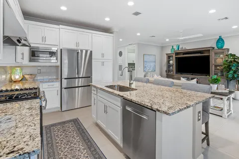 a kitchen with stainless steel appliances granite countertop a refrigerator stove microwave and sink