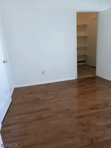a view of an empty room with closet and wooden floor