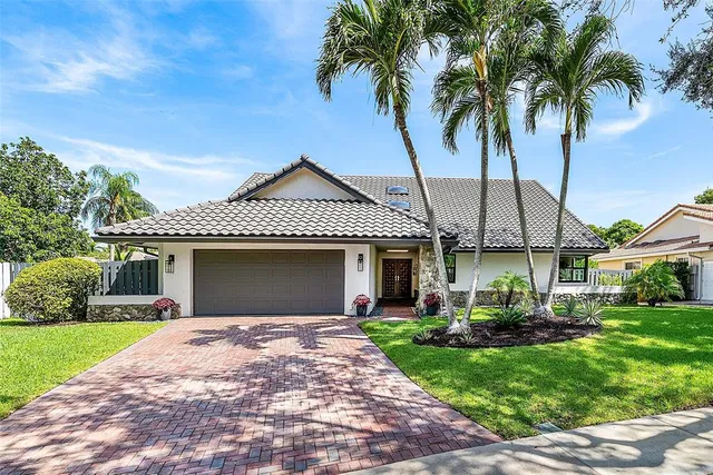 a front view of a house with a garden and palm trees