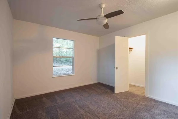 en empty room with windows and ceiling fan