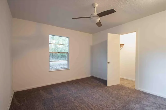en empty room with windows and ceiling fan