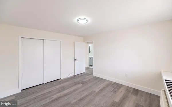a view of an empty room with wooden floor and closet