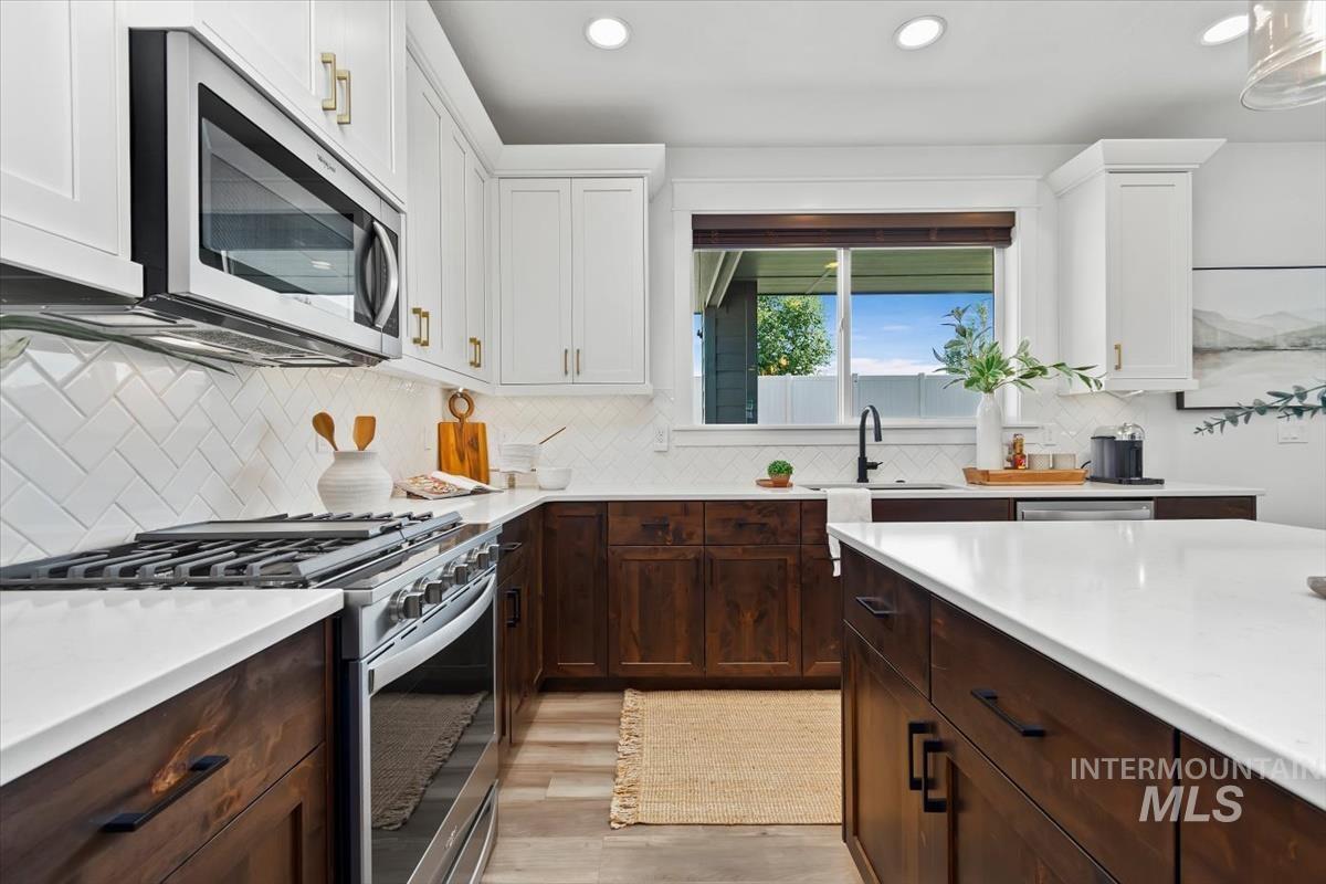 5897 West Riva Capri Street Meridian, ID 83646 - Photo 3 of 50 Modern kitchen featuring two-tone cabinetry with white upper and wood-finish lower units
