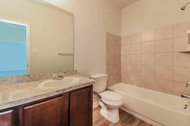 a bathroom with a granite countertop bathtub sink mirror vanity and toilet