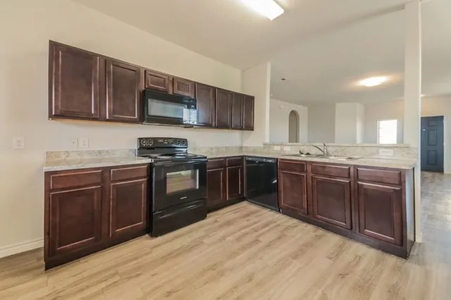 a kitchen with stainless steel appliances granite countertop wooden cabinets sink and stove