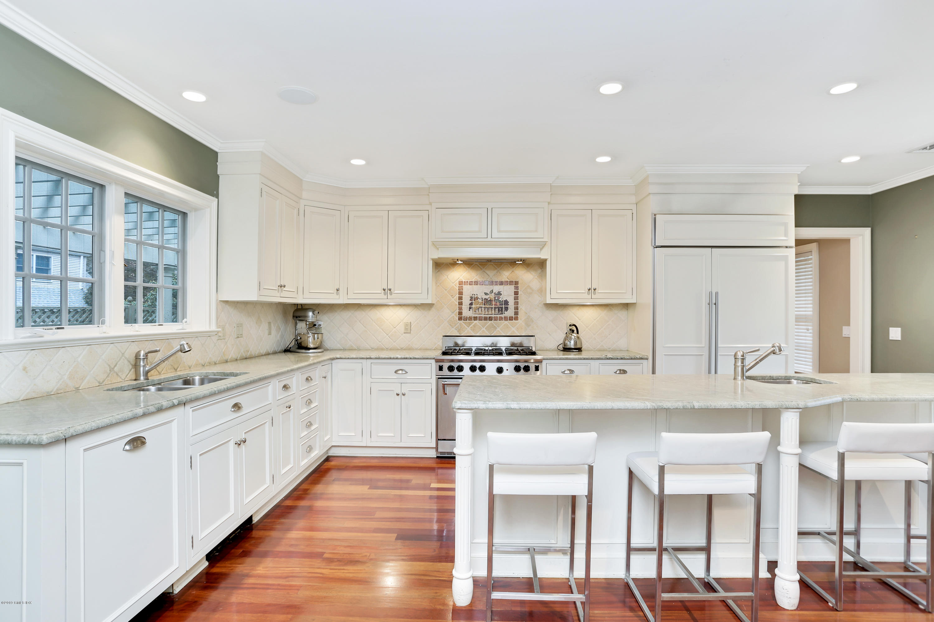 99 Lockwood Road Riverside, CT 06878 - Photo 7 of 21 a large white kitchen with stainless steel appliances granite countertop a stove top oven a sink a dining table and chairs