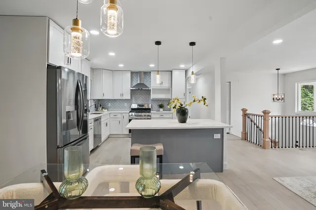 a kitchen with kitchen island a stove a refrigerator and a dining table with wooden floor