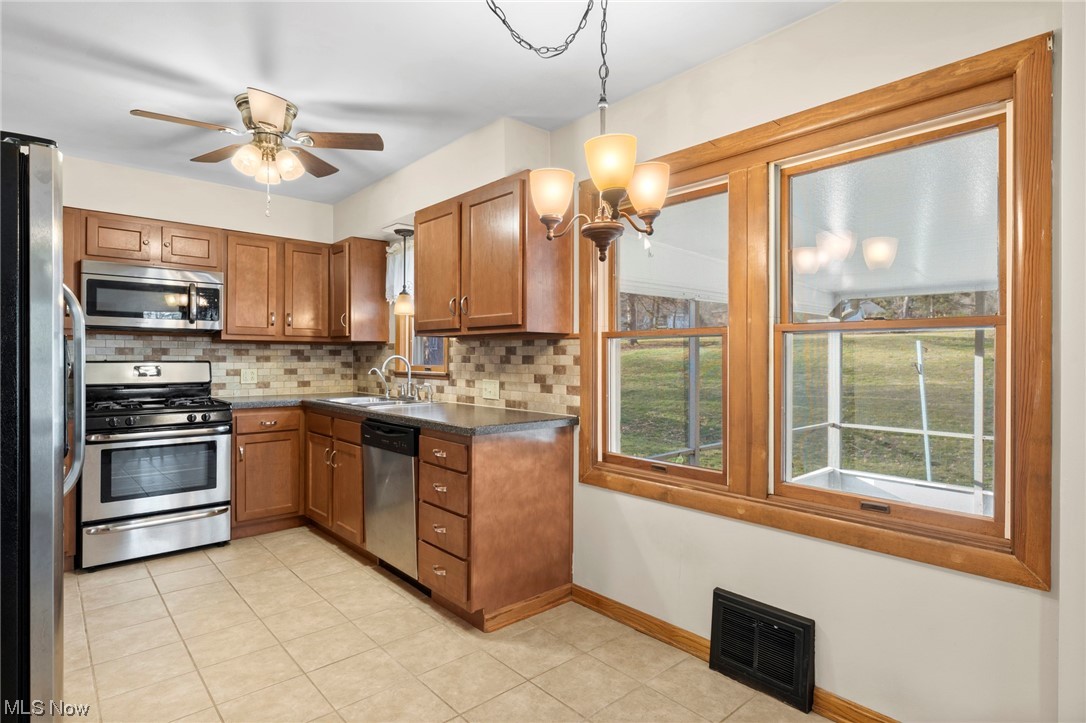 227 South Messner Road New Franklin, OH 44319 - Photo 23 of 44 Kitchen featuring backsplash, hanging light fixtures, ceiling fan with notable chandelier, light tile floors, and appliances with stainless steel finishes