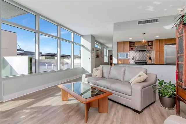 a kitchen with stainless steel appliances granite countertop a refrigerator a stove a sink dishwasher and a dining table with wooden floor