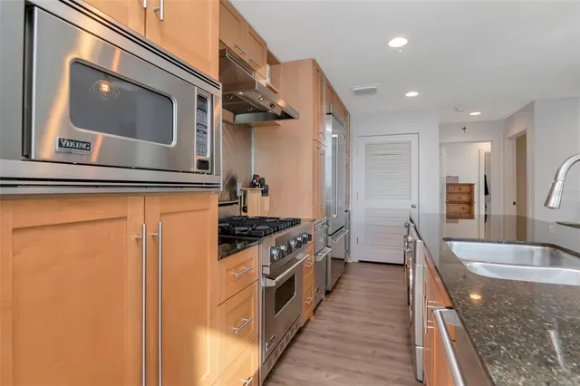 a kitchen with kitchen island a counter top space a sink a refrigerator and a view of living room