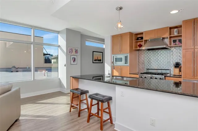 a kitchen with stainless steel appliances granite countertop a sink a stove and a wooden floors