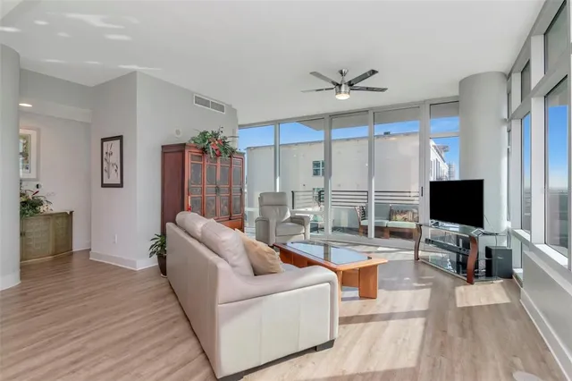 a living room with furniture a flat screen tv and floor to ceiling window