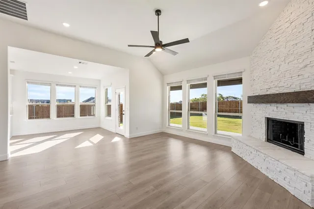 a view of an empty room with wooden floor fireplace and a window