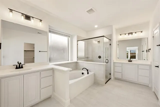 a bathroom with a tub a sink a mirror and shower