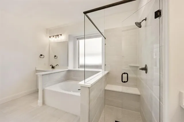 a bathroom with a tub a mirror and a shower