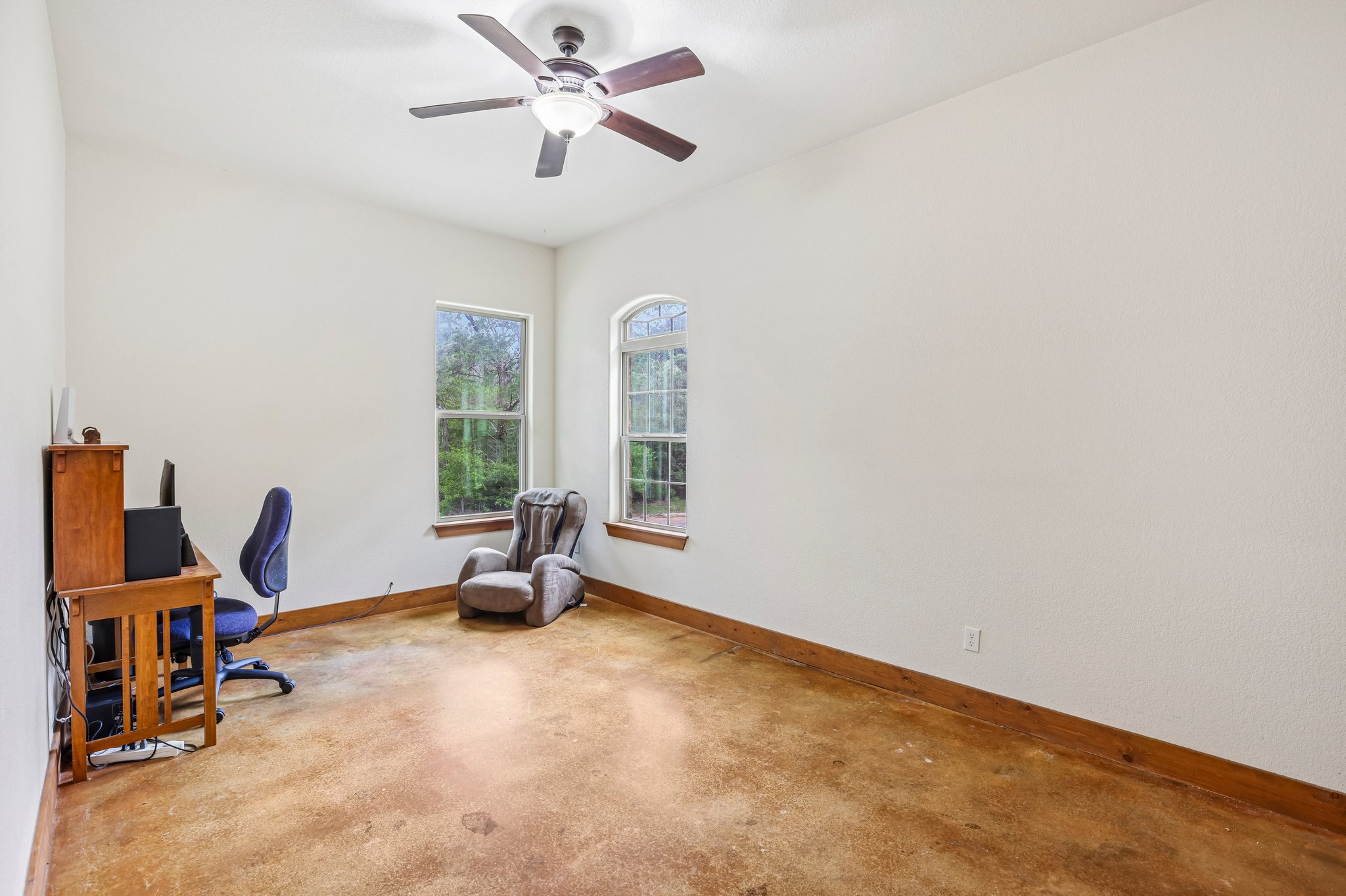 267 Corral Road Smithville, TX 78957 - Photo 23 of 40 Bright room featuring two large windows with natural wood trim, a ceiling fan with integrated lighting, and stained concrete flooring