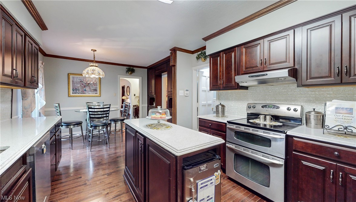 785 Merriman Road Akron, OH 44303 - Photo 12 of 34 Kitchen with dark hardwood flooring, hanging light fixtures, backsplash, stainless steel appliances, and ornamental molding