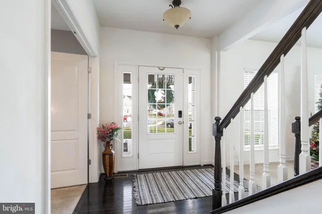 a kitchen with stainless steel appliances kitchen island granite countertop a refrigerator a stove top oven a sink dishwasher and white cabinets with wooden floor