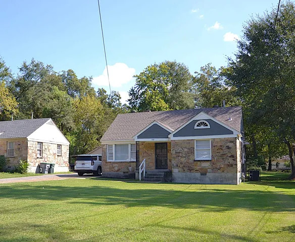 a front view of a house with a garden and trees