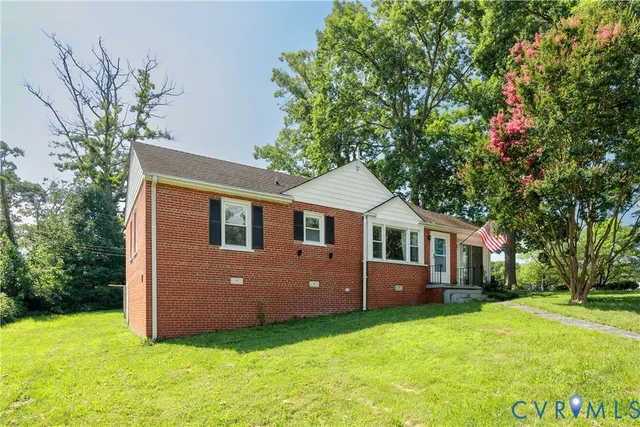 a front view of a house with yard and tree