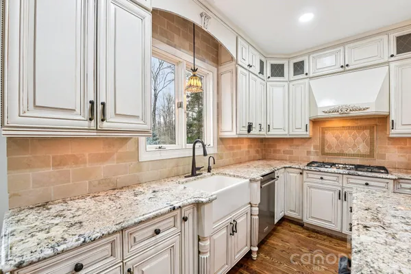 a kitchen with granite countertop a sink a stove and cabinets