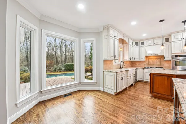a kitchen with stainless steel appliances granite countertop a stove a sink and a refrigerator with wooden floors