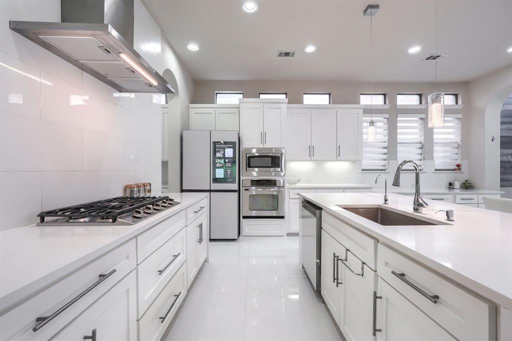 2246 Longview Road Irving, TX 75063 - Photo 10 of 40 Contemporary kitchen featuring white cabinetry, a gas cooktop with a stainless steel range hood, stainless steel appliances, and an island with an undermount sink