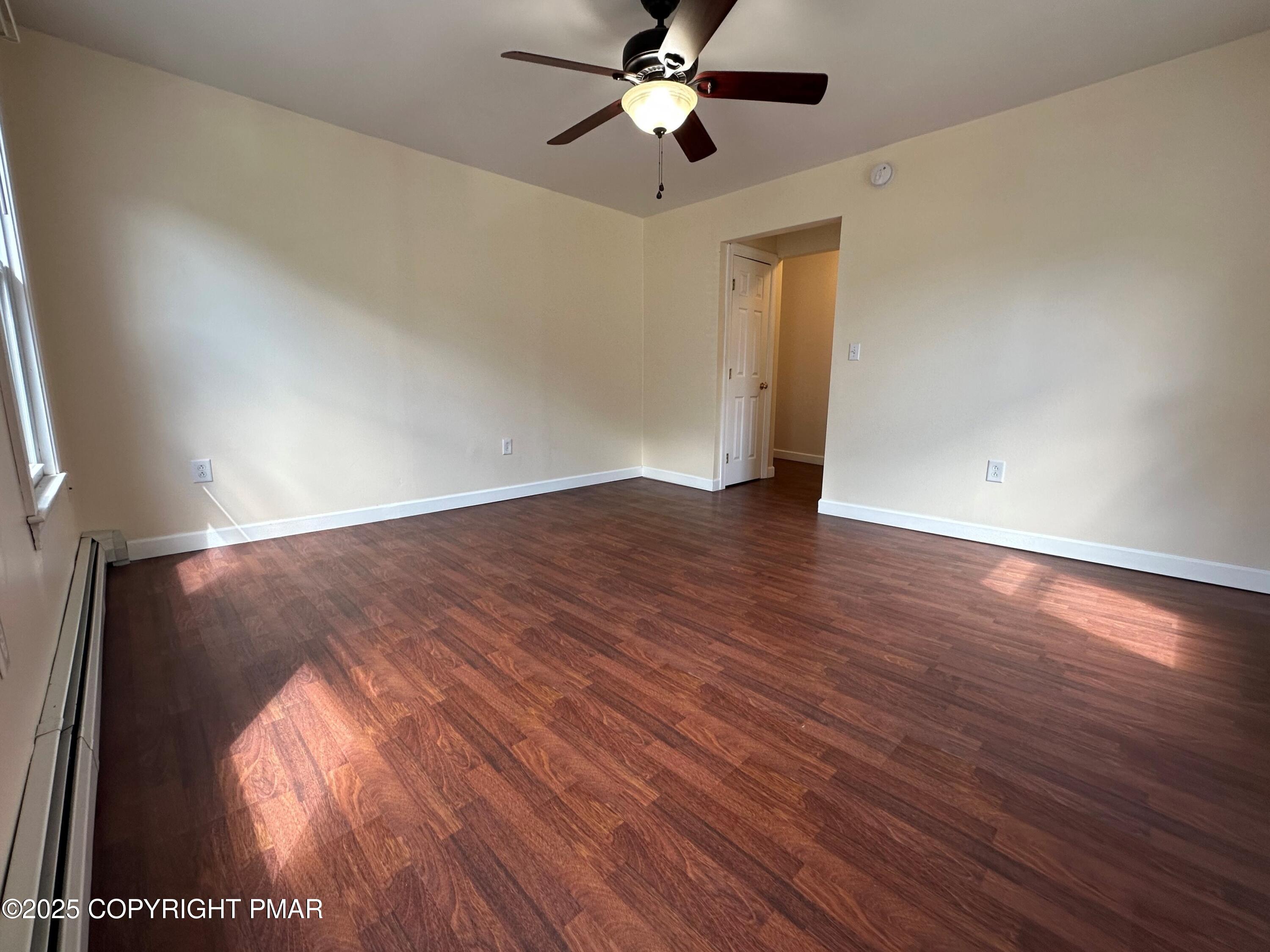 315 South 2nd Street Bangor, PA 18013 - Photo 3 of 27 an empty room with wooden floor a ceiling fan and a window