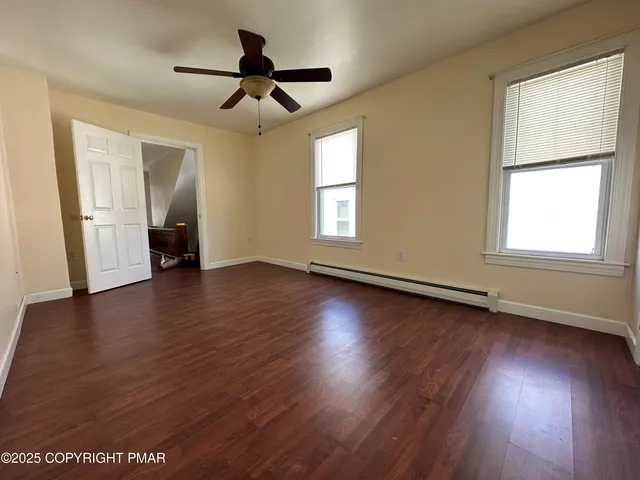 a view of empty room with wooden floor and fan