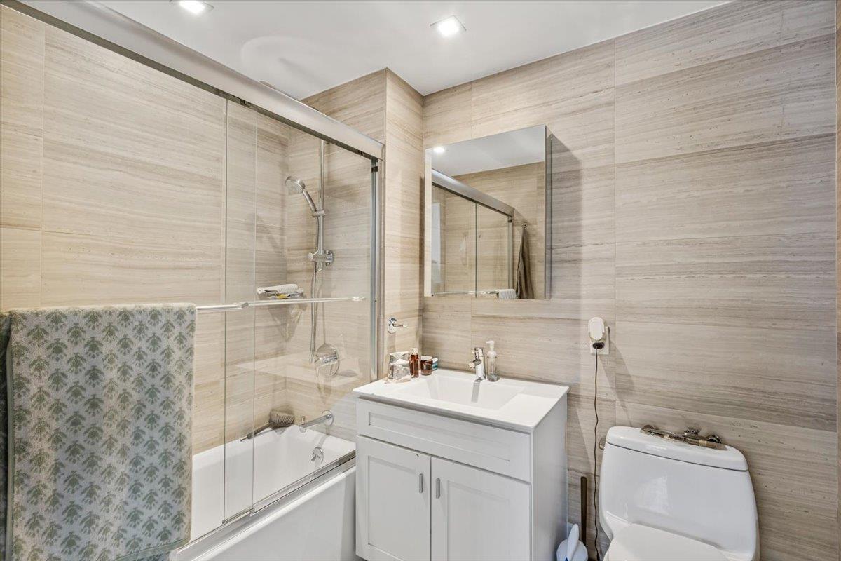 87-22 51st Avenue, Unit 4H Queens, NY 11373 - Photo 9 of 17 Full bath with toilet, enclosed tub / shower combo, vanity, and tile walls