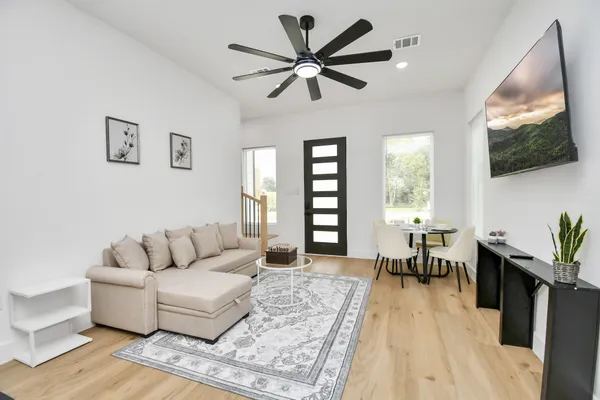 a living room with furniture a flat screen tv and a large window