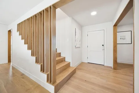 a view of a hallway with wooden floor and staircase