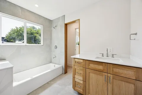 a bathroom with a tub sink and mirror