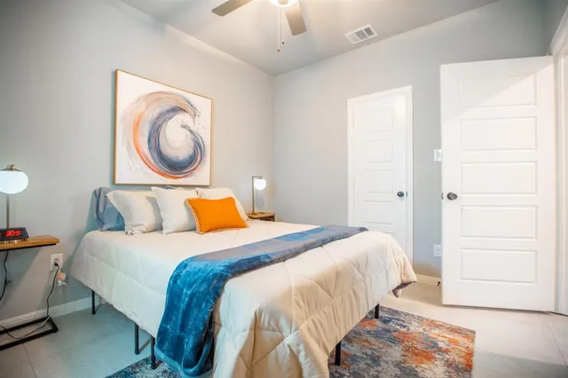 a bedroom with a bed and a lamp on dresser