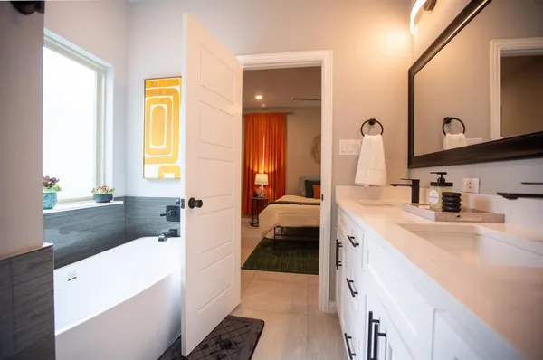 a en suite bathroom with a sink a tub and a mirror