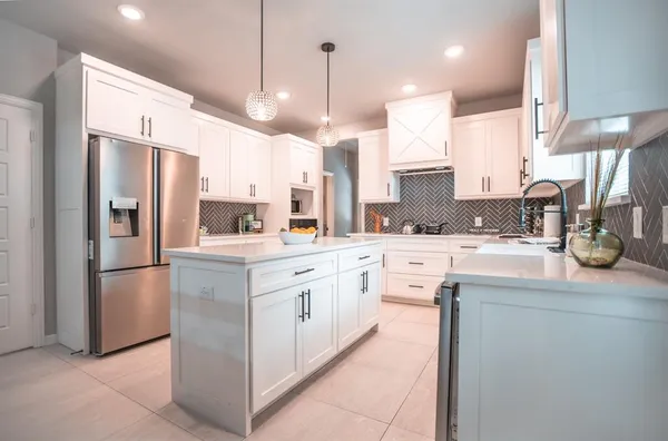 a kitchen with stainless steel appliances kitchen island granite countertop a refrigerator a sink and a oven