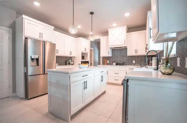 a kitchen with stainless steel appliances kitchen island granite countertop a refrigerator a sink and a oven