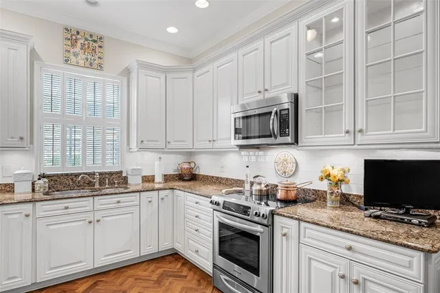a kitchen with stainless steel appliances granite countertop white cabinets sink and a granite counter top