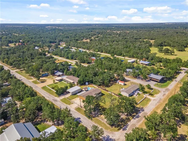 an aerial view of residential houses with outdoor space and trees