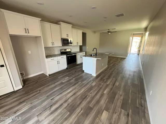 a open kitchen with cabinets wooden floor and stainless steel appliances