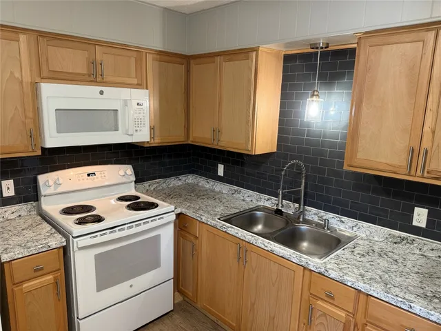 a kitchen with granite countertop a sink a stove and cabinets