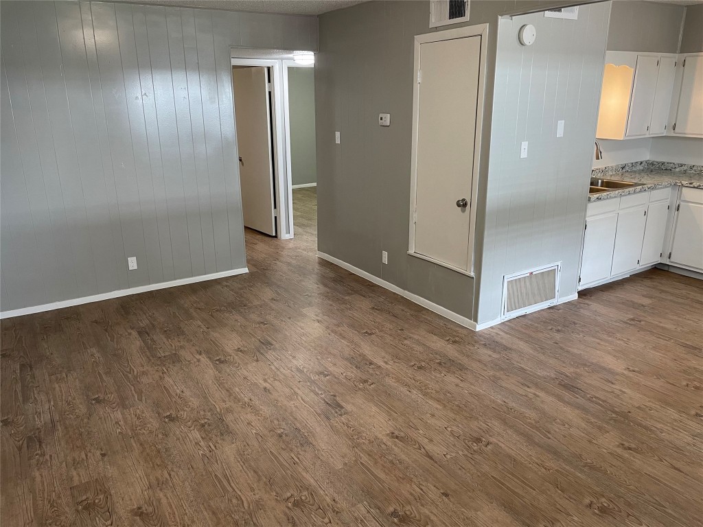 1209 Vance Street, Unit 30 Taylor, TX 76574 - Photo 22 of 35 an empty room with kitchen space and wooden floor
