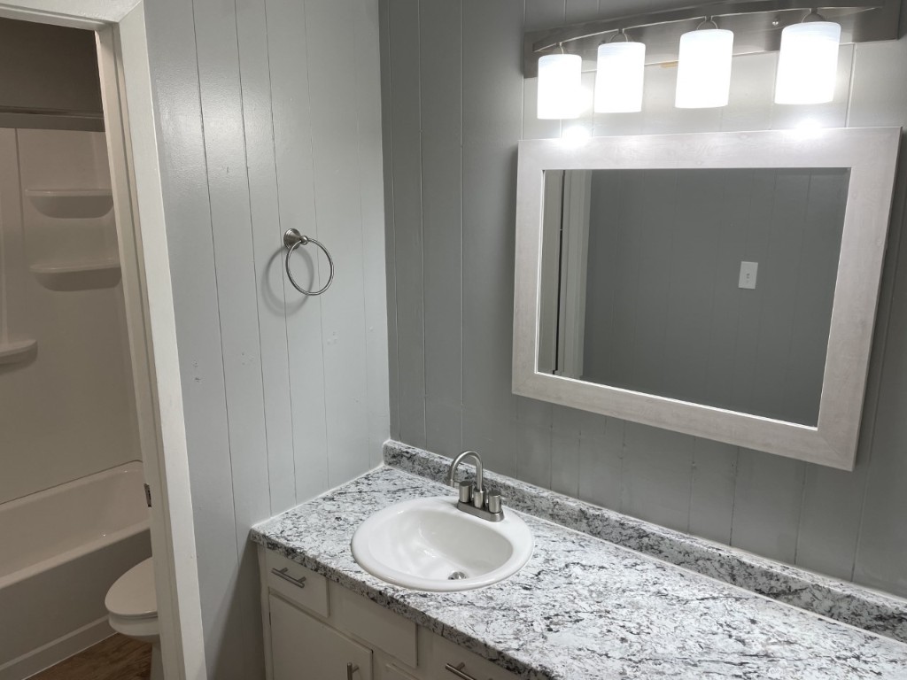 1209 Vance Street, Unit 30 Taylor, TX 76574 - Photo 27 of 35 a bathroom with a sink vanity granite toilet and a mirror
