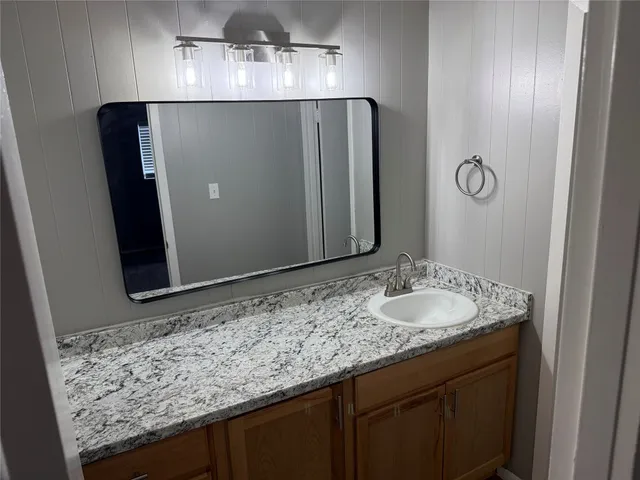 a bathroom with a granite countertop sink and a mirror